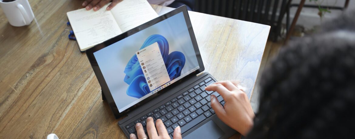 Overhead view of two people at a table working with a Microsoft laptop and notebook