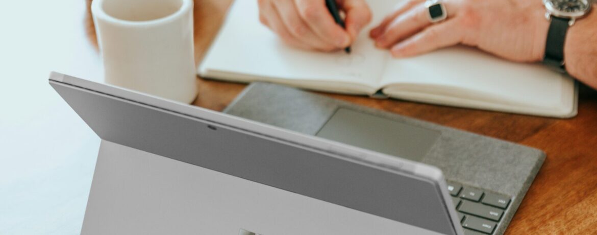 a man sitting at a table writing on a notebook