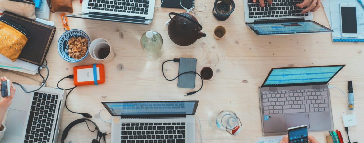 people sitting down near table with assorted laptop computers